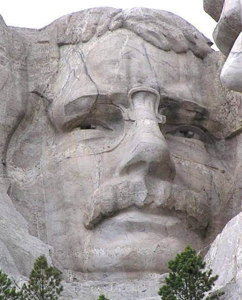 Which president depicted on mount rushmore is wearing glasses