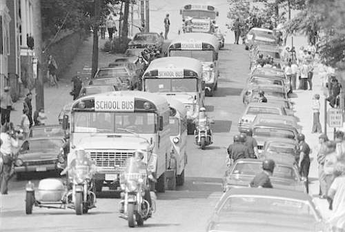 Caption: motorcycle police escort school buses as they leave south boston high school at the end of